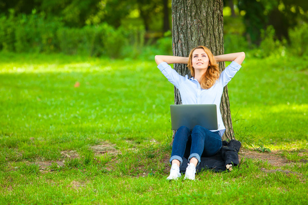 ラップトップの公園で座っている美しい女性 - 写真・画像