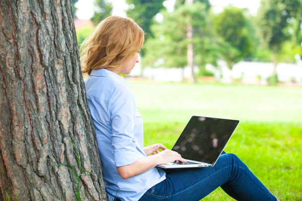 beautiful woman sitting in park with laptop - Foto, Bild