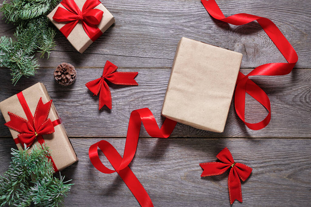 packing christmas gifts on a wooden table, craft paper and red ribbon, free space, new year gifts 2022 - Photo, Image