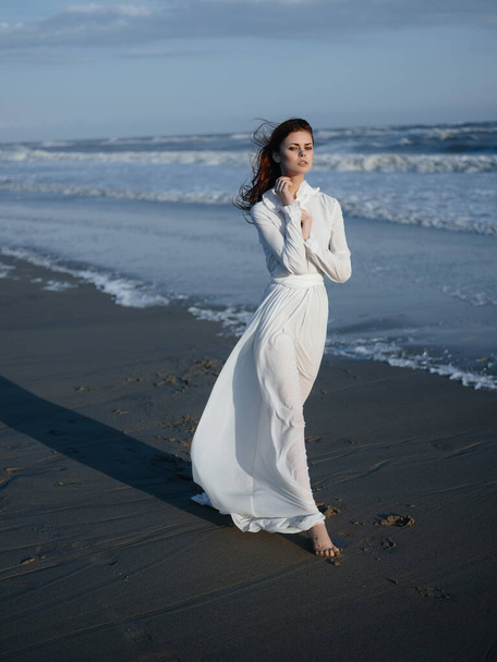 Жінка в білій сукні ходить босоніж на піщаному океані свіжі повітряні подорожі
 - Фото, зображення