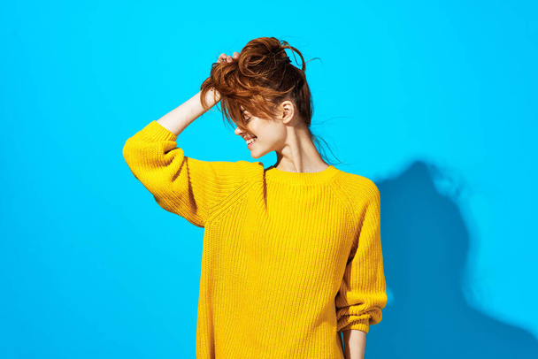 nő sárga pulóver pózol divat frizura kék háttér - Fotó, kép