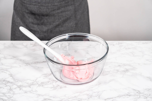 Mixing in store-bought buttercream frosting in a glass mixing bowl. - Zdjęcie, obraz