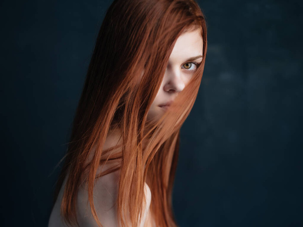 red-haired woman naked shoulders clear skin dark background - Fotoğraf, Görsel