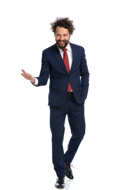 attractive businessman walking towards the camera with one hand in pocket and the other one open - Photo, Image