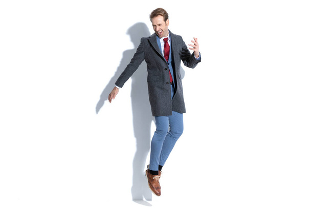 schöner Geschäftsmann springt vor weißem Hintergrund aufgeregt in die Luft - Foto, Bild