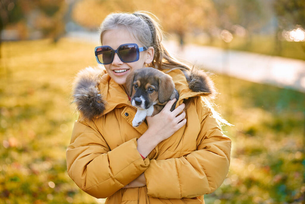 Girl smiling and hugging cute puppy outdoors. - Fotó, kép