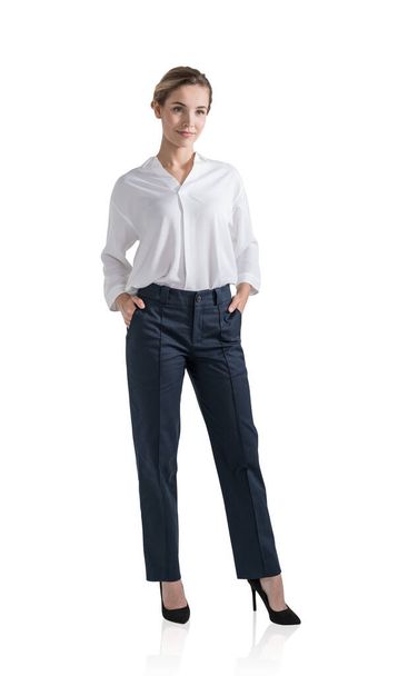 Young attractive businesswoman wearing blouse and trousers is standing in hands in pocket pose. Concept of contemporary successful business people. Isolated over white background - Photo, Image