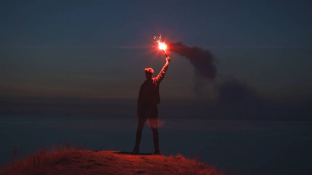 Человек с огненной палкой на вершине горы у моря - Фото, изображение