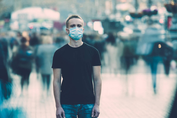 El hombre con máscara médica en la cara está en medio del flujo humano - Foto, imagen