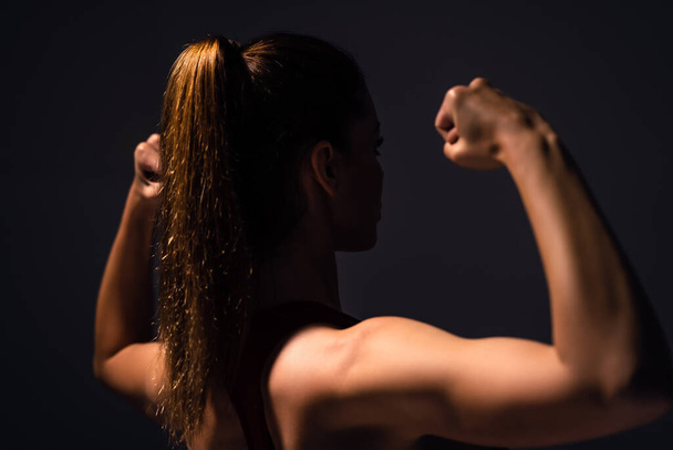De mooie vrouw in sportkleding demonstreert haar biceps - Foto, afbeelding