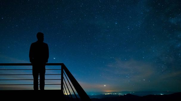 Muž stojící na balkóně na hvězdném pozadí oblohy - Fotografie, Obrázek