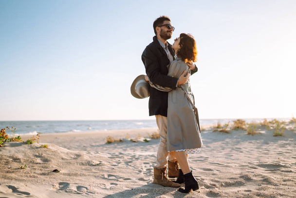 Young couple having fun walking and hugging on beach during autumn sunny day. Relaxation, youth, love,  lifestyle solitude with nature. - Foto, imagen