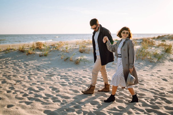 Young couple having fun walking and hugging on beach during autumn sunny day. Relaxation, youth, love,  lifestyle solitude with nature. - Foto, Imagem