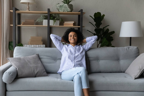 Tranquil teenage black female chill on comfy couch at home - Foto, afbeelding