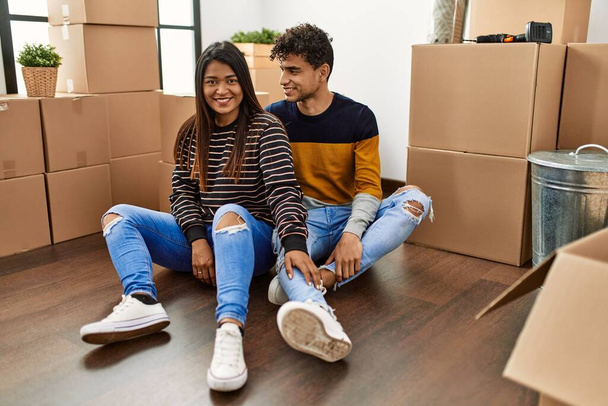 Young latin couple smiling happy sitting on the floor at new home. - Fotoğraf, Görsel