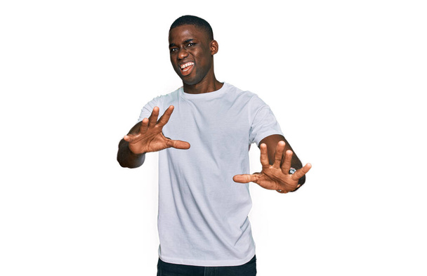 Young african american man wearing casual white t shirt afraid and terrified with fear expression stop gesture with hands, shouting in shock. panic concept.  - Photo, Image