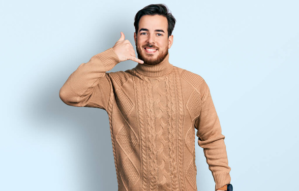 若いヒスパニック系の男性は、携帯電話で話すような手や指で携帯電話のジェスチャーを行う笑顔カジュアルな服を着ている。コミュニケーションの概念.  - 写真・画像