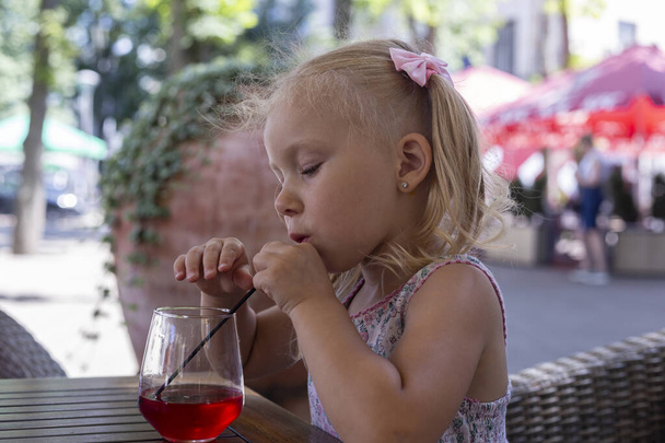 Lapsi juo juomaa kesäterassilla luonnonvalossa. Oikeat ihmiset. - Valokuva, kuva