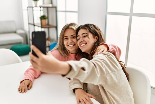 Молодая пара улыбается счастливо делая селфи на смартфоне дома. - Фото, изображение