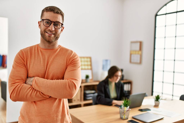 Empresário sorrindo feliz com braços cruzados gesto de pé no escritório. - Foto, Imagem