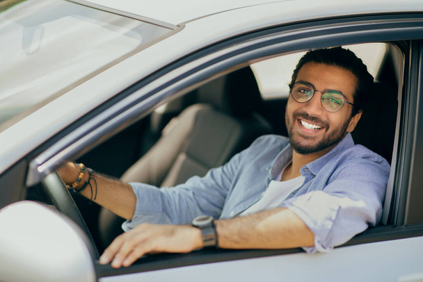 Πορτρέτο του χαρούμενου αραβικού τύπου που κάθεται μέσα στο ολοκαίνουργιο αυτοκίνητο - Φωτογραφία, εικόνα
