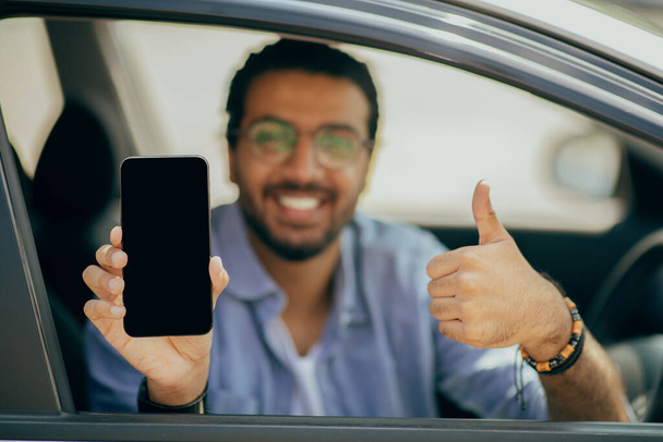 Felice arabo uomo driver in possesso di cellulare con schermo vuoto, mockup - Foto, immagini