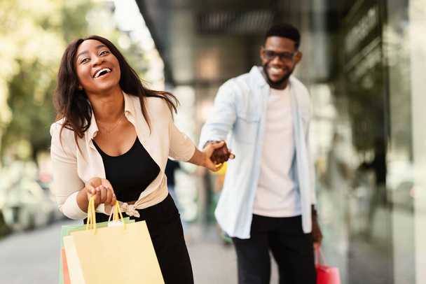 excité noir femme tirant petit ami à shopping magasin - Photo, image