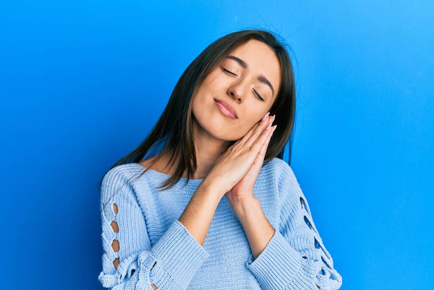 Young hispanic girl wearing casual clothes sleeping tired dreaming and posing with hands together while smiling with closed eyes.  - Photo, Image