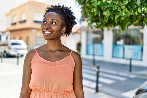 A fiatal afro-amerikai nő boldogan mosolyog a városban egy nyári napon. - Fotó, kép