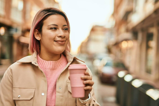Young hispanic girl smiling happy drinking coffee at the city. - Photo, Image