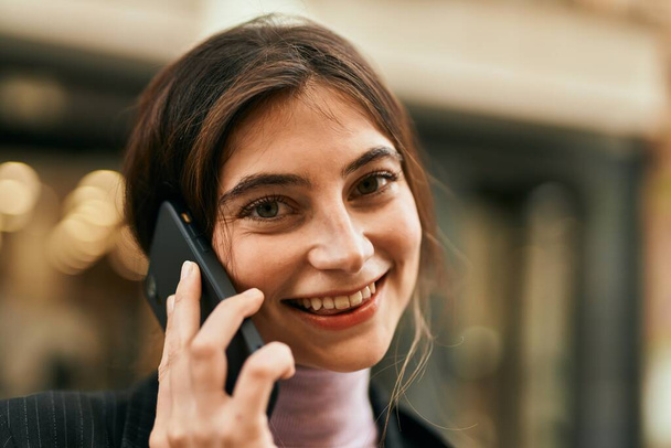 Fiatal gyönyörű üzletasszony mosolyog boldog beszél az okostelefonon a városban. - Fotó, kép