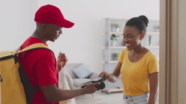 Femme afro-américaine gaie payer pour la commande de nourriture du marché avec smartphone, obtenir sac de courrier à la maison - Séquence, vidéo