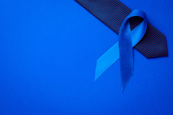 Hombres cancerosos. Concienciación sobre el cáncer de próstata de los hombres salud en noviembre. Cinta azul, corbata de moda aislada sobre fondo azul profundo. Apoyar a las personas que viven y enferman - Foto, Imagen