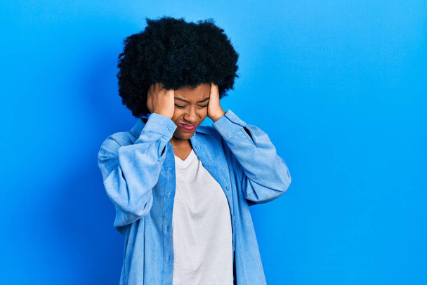 Junge afrikanisch-amerikanische Frau in lässiger Kleidung leidet unter Kopfschmerzen verzweifelt und gestresst, weil Schmerzen und Migräne. Hände auf den Kopf.  - Foto, Bild