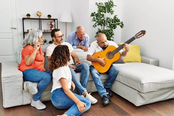 Group of middle age friends having party playing classical guitar sitting on the sofa at home. - Fotoğraf, Görsel