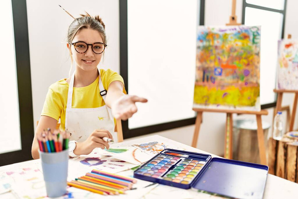 Giovane bruna adolescente presso lo studio d'arte sorridente allegra offerta mano di palma dando assistenza e accettazione.  - Foto, immagini