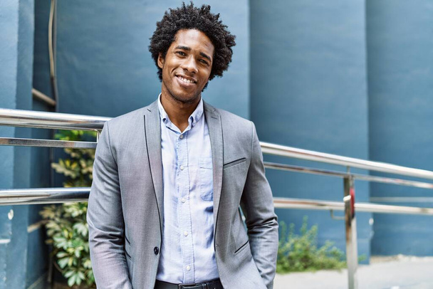 Giovane uomo d'affari afroamericano sorridente felice in piedi alla città. - Foto, immagini
