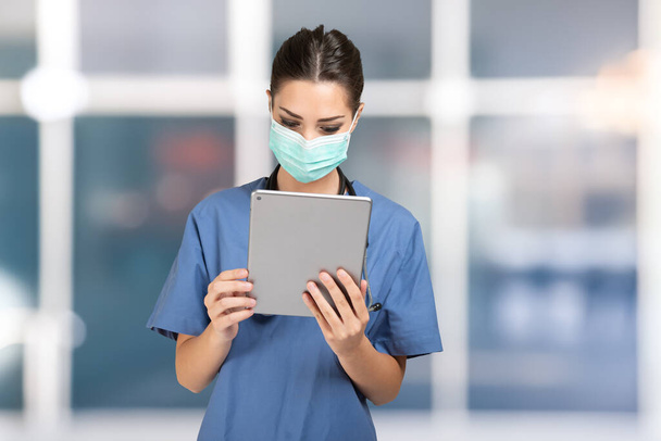 Young nurse using a mobile tablet app - Foto, afbeelding