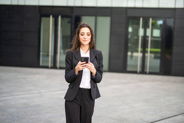 Smiling young business woman using her mobile cell phone - Zdjęcie, obraz