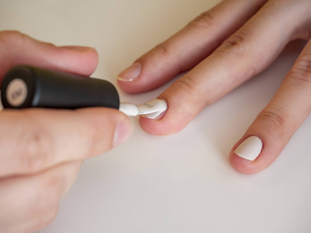 aanbrengen van witte nagellak op de nagel. Manicure en nagelverzorging concept - Foto, afbeelding