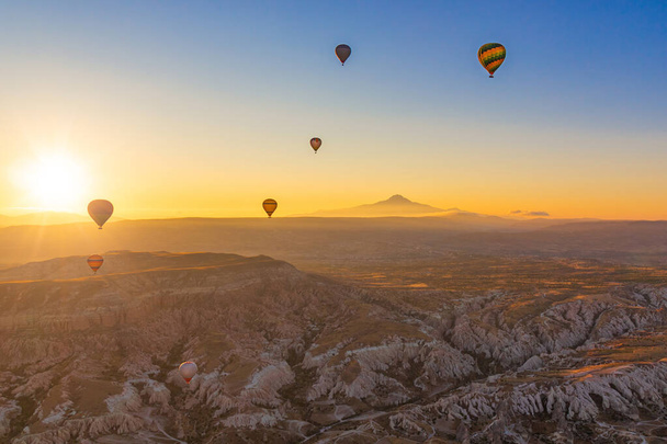 Hot air balloons on the background of the rising sun and mountains in Cappadocia. Turkey flying in the air. - Фото, зображення