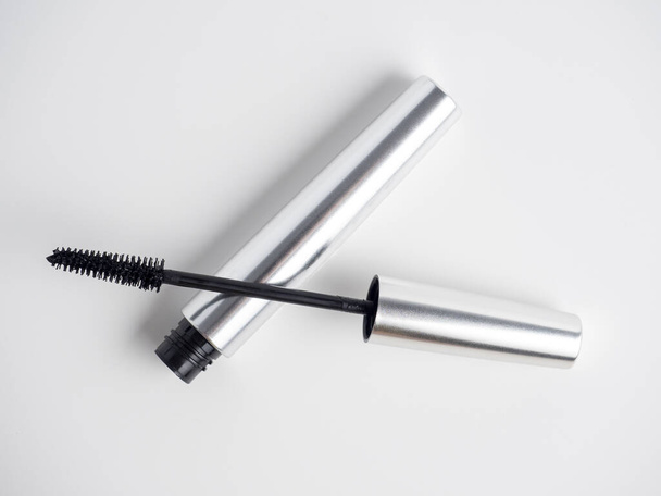 mascara in a silver tube lies on a white background. A brush for applying mascara. Cosmetology, self-care. Women's beauty - Fotografie, Obrázek