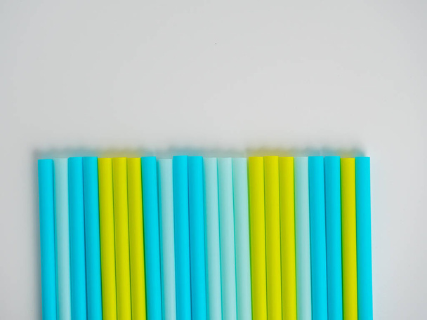 Multicolored plastic tubes are laid out on a white paper background. Top view, flat lay - Photo, Image