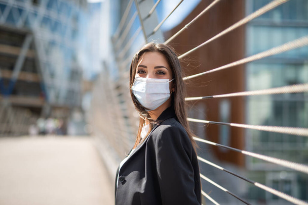 Portrait of a young masked woman near a bridge, covid and coronavirus pandemic concept - Photo, image