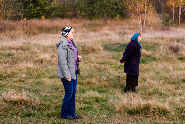 Versla twee vrouwen tijdens een wandeling in de herfstnatuur. Achtergrondinformatie. Prachtig parklandschap. Twee vrouwen lopen langs de weg in het herfstbos. Zijaanzicht. Onscherp.. - Foto, afbeelding