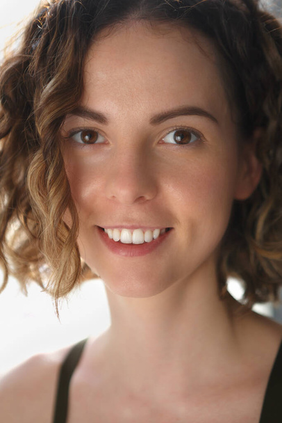 Portrait of beautiful curly young woman in mid 20s. Friendly and cheerful female model with toothy smile - Photo, image