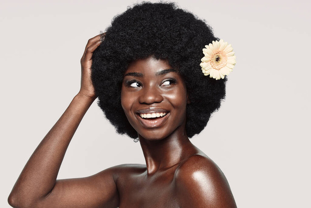 Portrait of beautiful young African woman touching hair and smiling - Valokuva, kuva