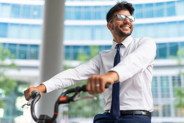 Smiling businessman parking his bicycle in front of the office - Photo, Image