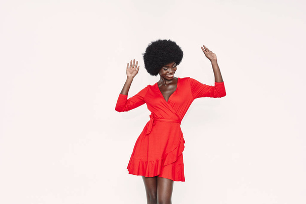 Beautiful young African woman in red dress dancing against background - Foto, afbeelding