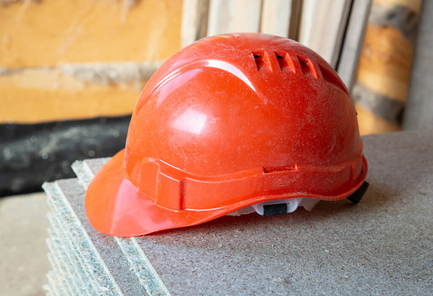 κράνος πορτοκαλί προστατευτικό εξοπλισμό του κατασκευαστή σε μια ξύλινη επιφάνεια - Φωτογραφία, εικόνα